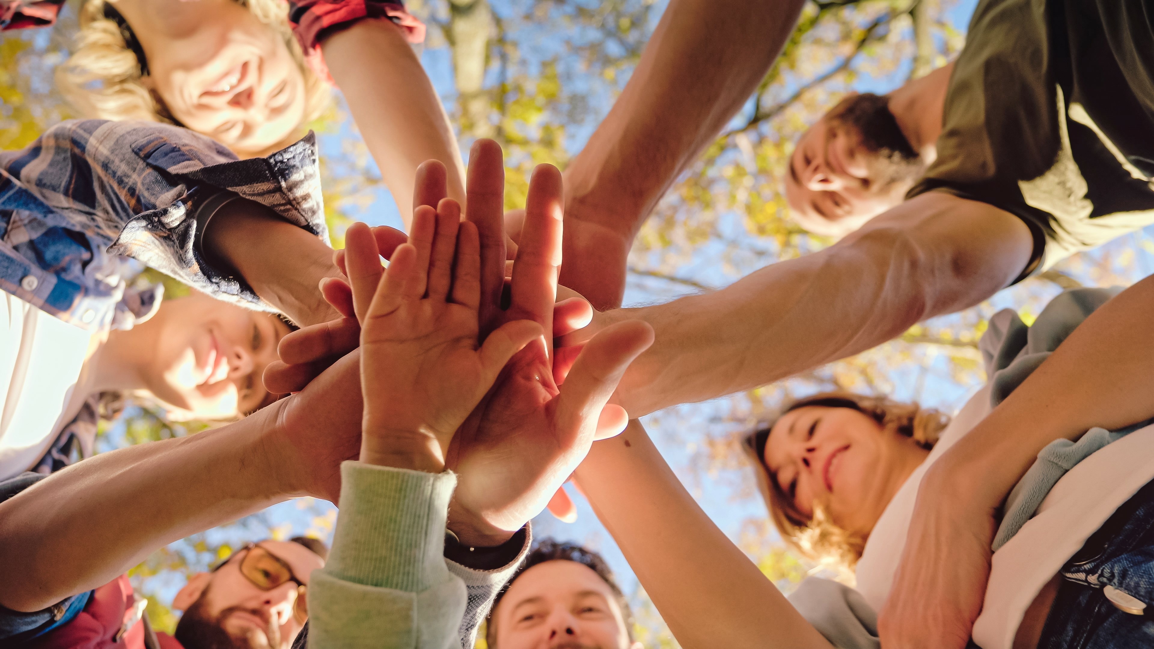 Close up from below on Caucasian activists, men and women with kid putting hand on hand in circle and making gesture of cooperation and coworking. Successful volunteering work together concept. Close up from below on Caucasian activists, men and women with kid putting hand on hand in circle and making gesture of cooperation and coworking. Successful volunteering work together concept.