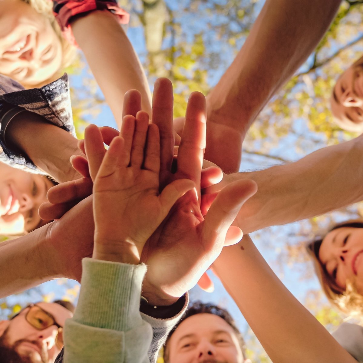 Close up from below on Caucasian activists, men and women with kid putting hand on hand in circle and making gesture of cooperation and coworking. Successful volunteering work together concept. Close up from below on Caucasian activists, men and women with kid putting hand on hand in circle and making gesture of cooperation and coworking. Successful volunteering work together concept.
